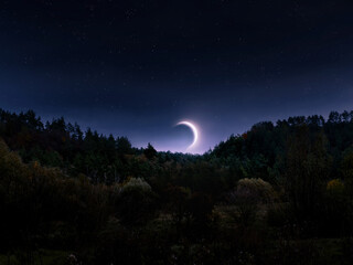 Moonrise in the evening sky. Crescent Moon above the horizon. Dreamy landscape with Earth satellite over the hills.