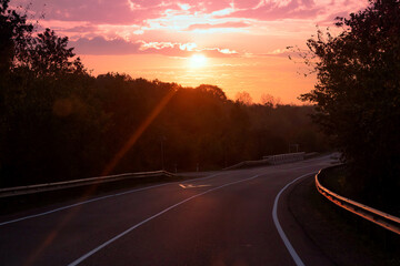 Empty long mountain road to the horizon on a sunny summer day at bright sunset - speed motion blur effect