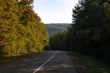 Empty long mountain road to the horizon on a sunny summer day at bright sunset - speed motion blur effect