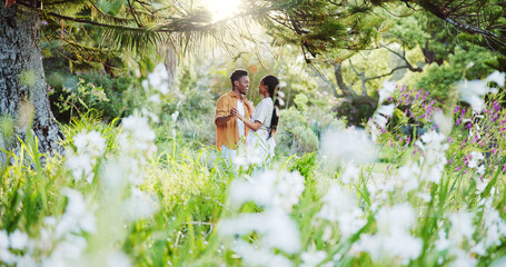 Dance, flowers and love with black couple in nature for romance, honeymoon date and bonding together. Celebration, happiness and spring with man and woman in park for relationship, support and care