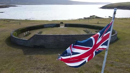 Waving union jack flag flutters over british war graves near the ocean, honoring the memory of fallen soldiers and their sacrifice - Powered by Adobe