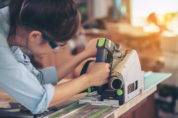 Close Up Portrait of a Young Female Artisan Carpenter Using Hand Plane to Shape a Wood Bar. Beautiful Artist Working on a Project in a Woodworking Workshop.