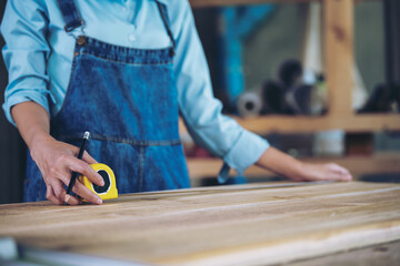 Small furniture business owner preparing equipment for work. Female carpenter adjusting wood to desired size. Architect, designer, built-in, professional woodworking, craftsman, factory.