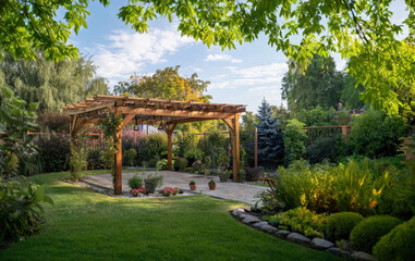 Beautiful Garden with Pergola and Lush Greenery
a beautifully landscaped garden featuring a wooden pergola as the central structure. The pergola is surrounded by lush greenery
