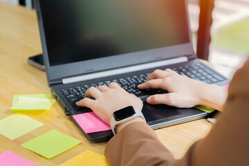 Young woman working at desk with laptop and post it notes all around.