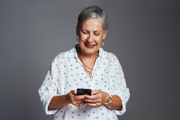 Studio, senior woman and smile with smartphone for communication, chat and online with contact. Mockup space, female person and happy with mobile app for conversation, social media or gray background
