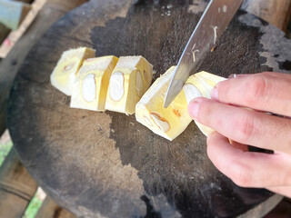 Cutting young jackfruit flesh into chunky pieces with knife background. To be cooked as meal. Asian...