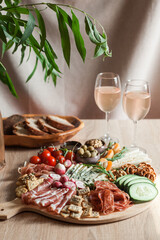 a person serving charcuterie board a platter of meat cheese crackers nuts olives and vegetables