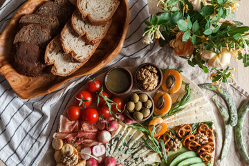 a person serving charcuterie board a platter of meat cheese crackers nuts olives and vegetables
