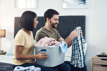 Happy couple, help and folding laundry on bed for support, shared chores and responsibility in home. Man, woman and clothes in bedroom for spring cleaning, sorting and routine housework on weekend