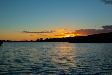 Orange colors over a river, a sunset with orange colors. The sky is tinged with warm tones, from...