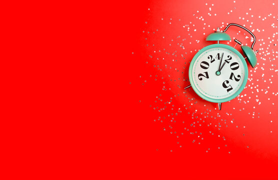 New Year 2025 background concept. 2024 changes to 2025 on an alarm clock on a colored background with festive glitter on New Year's Eve and Christmas.