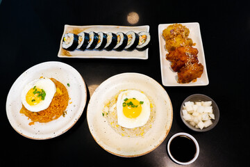Korean foods served on a dining table,Gimbap,Fried chicken, radish,kimchi,spicy sauce with rice, seaweed,bibimbap,kimbap,Kimchi fried rice with fried egg and scallion sprinkle,copy space.