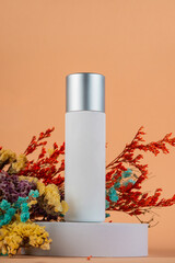 Cosmetic product in tube, bottle, lotion or serum and dried flowers on cream background. 