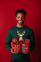Fototapeta premium Man smiling and wearing sweater with deer and holding gifts and presents on minimalistic red background and studio light. Bright Christmas vertical banner for winter season sale or invitation