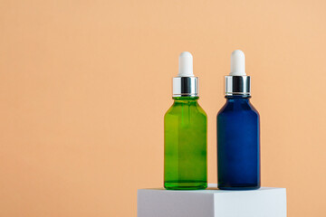 Blue and green glass cosmetic bottle, Skin care or sunscreen cosmetic with stylish props on cream background.