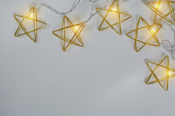 Golden metal garland with lights on gray background with copy space