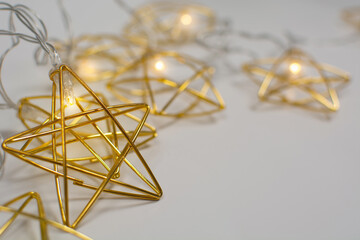 Golden metal garland with lights on gray background with copy space