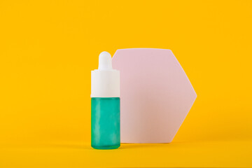 Blue glass cosmetic bottle, Skin care or sunscreen cosmetic with stylish props on yellow background.