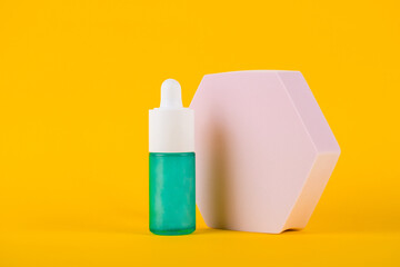 Blue glass cosmetic bottle, Skin care or sunscreen cosmetic with stylish props on yellow background.