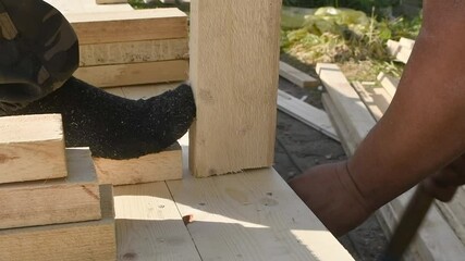 A worker finishing the assembly of a wooden structure, hammering a nail into a vertical beam, illustrating the construction process within the concept of a wooden frame house