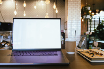 Blank laptop screen on wooden table with coffee shop interior background and blurred bokeh lights. Mockup model. Template for your text.