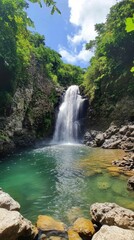 Water cascades down rocky cliffs into a calm pool, framed by vibrant plants under a bright sky