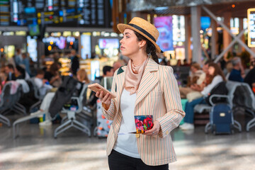 Side view of Caucasian young woman in straw hat holds passport and using smartphone. Online checking flight. The concept of vacation and flight trip