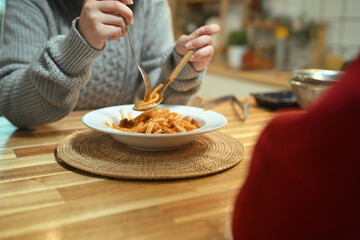 Young woman enjoying a homemade pasta dish during the holidays in a kitchen