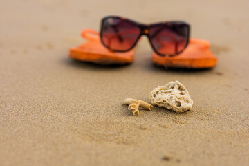 White coral pieces and defocused orange flip-flops on a sandy beach. Simple but impactful...