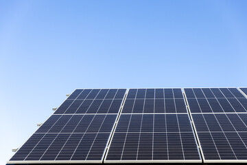 Obraz premium Aerial view of solar panel cells on clear blue sky background. Clean alternative energy power concept, sustainable resources. Modern house, solar panels stand-alone photovoltaic plant system on roof