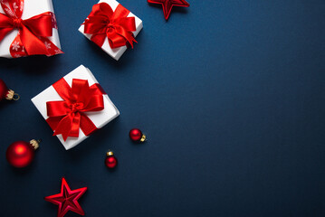 Merry Christmas and Happy Holidays greeting card, frame, banner. New Year. Noel. Red and white Christmas ornaments and gifts on blue background top view. Winter xmas holiday festive theme.	
