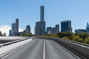Fototapeta premium Curved road leading to Manhattan skyscrapers with clear sky background.