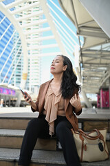 Portrait of elegant senior businesswoman relaxing on the steps in modern cityscape