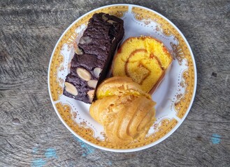 many cakes in one plate such as bronis chocolate cake, sus cake and rolled pineapple flavored cake