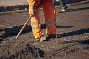 Construction workers working on a new asphalt layer on a public street.