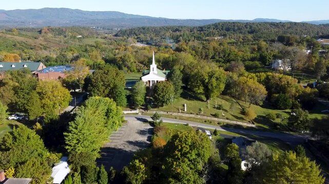 Drone flying over a neighborhood surrounded by lush trees towards Fincastle Presbyterian Church
