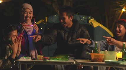 Multi-ethnical Group Of Friends Playing Truth Or Dare Game At Night Around Campsite