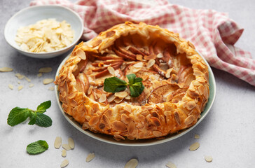 Delicious homemade apple galette with almond flakes and fresh mint on table