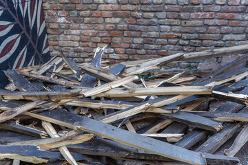 Pile of wood is scattered on the ground, with some of it being burnt