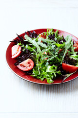 Salad with fresh tomatoes and arugula on a bright background. Close up. Copy space.