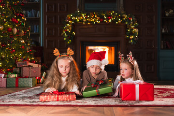 Merry Christmas Xmas holiday. Children unpacking open up gift box near Christmas tree. Kids in...
