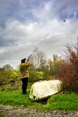A man with a shotgun shooting a pheasant