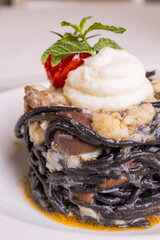 Spaghetto al nero di seppia con sugo di pesce, seppie, olive e ricotta servito in un ristorante elegante come primo piatto