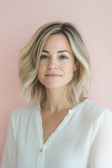 Fototapeta premium A woman with blonde hair smiles, wearing a white blouse.