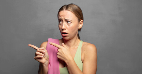 Obraz premium feeling shocked and surprised, pointing to copy space on the side with amazed, open-mouthed look