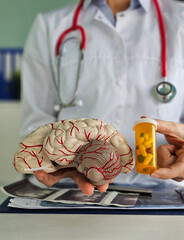 Doctor holding brain model and pills in clinic. Nootropics with proven effectiveness for brain...