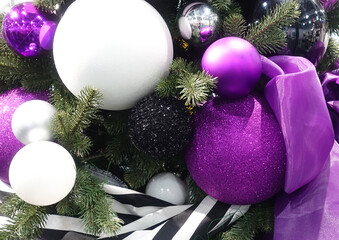 Beautiful white and purple Christmas balls with ribbons decorate the Christmas tree close-up.