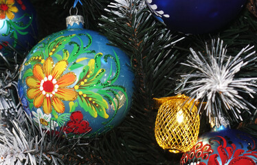 A Christmas ball with a hand painted flower hangs on the tree.