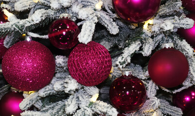 Beautiful burgundy Christmas balls on a snowy Christmas tree.
